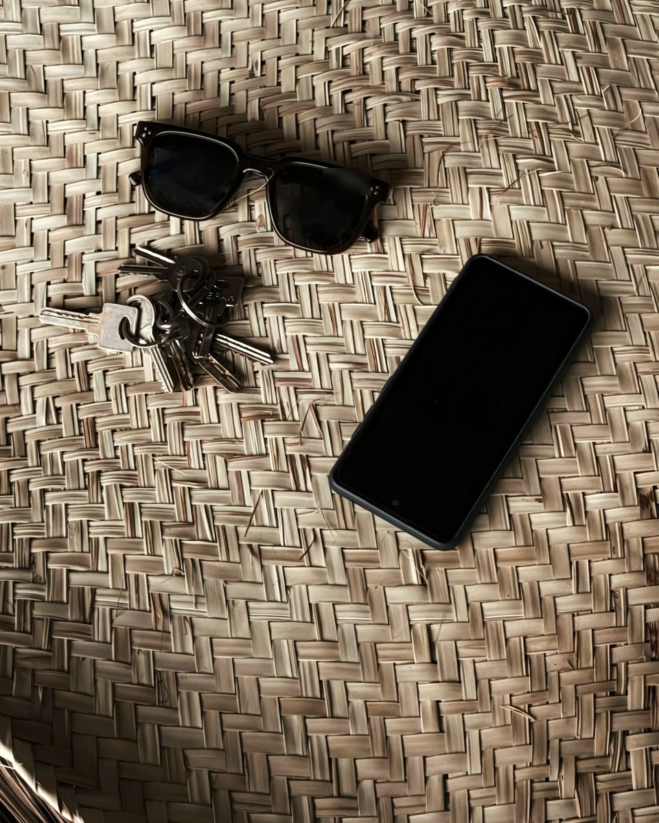 Keys, sunglasses and a phone on a woven mat